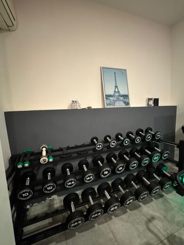 Kundenbild der Rundhanteln PRO, die ordentlich auf einem schwarzen, mehrstufigen Hantelständer in einem Heimstudio angeordnet sind.