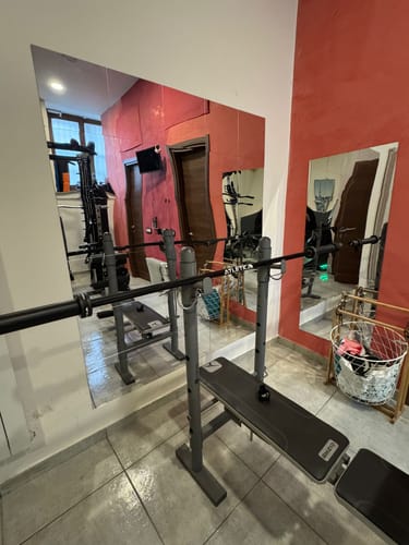 Kunde zeigt das aufgebaute Set Delta Tripple Black mit Hantelbank und Langhantel in einem Fitnessraum.