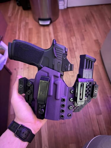 Customer's hand holding the purple APX holster with a handgun and a spare magazine, showcasing its modular design.