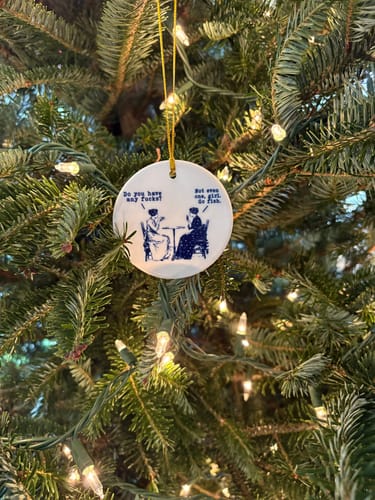 Reviewer's funny ornament hanging on a lit Christmas tree.