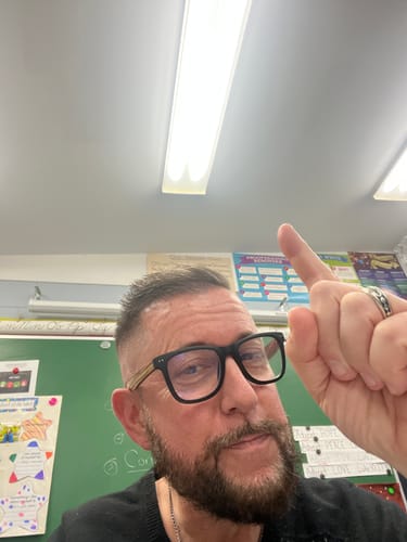 Reviewer in a classroom wearing the ALDEN BLUE LIGHT READERS, showing the black square frames and contrasting arms.
