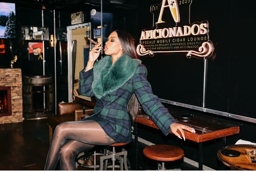 Reviewer sitting in a lounge wearing the Suiting Plaid Faux Fur Blazer with its plush collar.