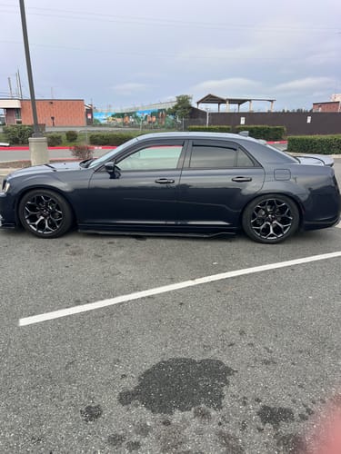 A customer's shiny, dark grey car parked in a lot after being detailed with the product.