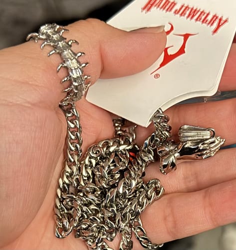 Customer holding the silver LORD, FORGIVE ME PENDANT and its attached chain in their hand.