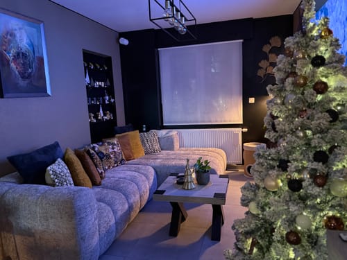 De beige Micadoni Lupine hoekbank van een klant in een sfeervol verlichte woonkamer met een kerstboom.