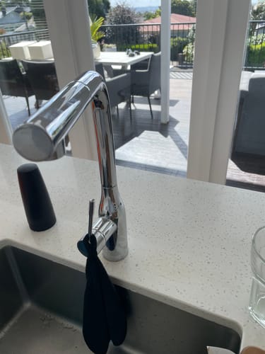 Customer's black KoalaCloth hanging on a sparkling chrome kitchen faucet.