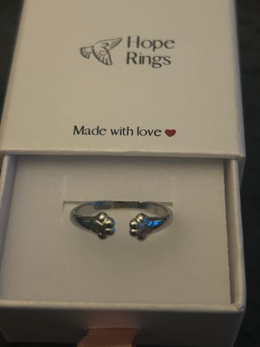 Customer's silver Paw Hug Ring resting inside its white branded gift box.