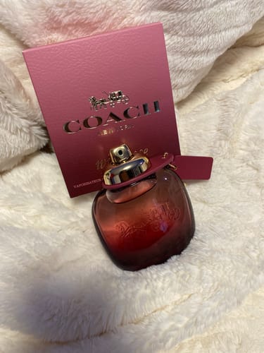 Customer's Coach Wild Rose Eau De Parfum bottle shown with its pink box on a fluffy white surface.