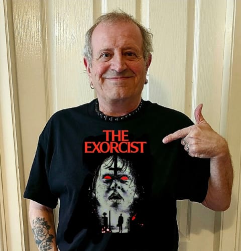 Customer smiling and pointing to the graphic on their black unisex t-shirt featuring 'The Exorcist'.