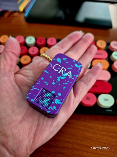 Reviewer holding a purple Nano Case with a turquoise splatter design in their palm.