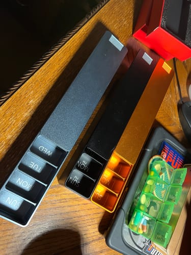 Customer's silver and gold Weekly AM-PM Vitamin XL Cases open on a desk, compared to a plastic pill case.