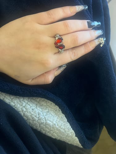 Customer's hand wearing the Promise Ring, showing its silver band and two red coffin-shaped stones.