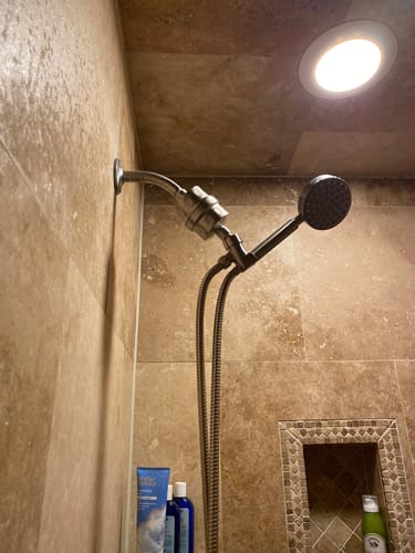 A customer's silver Shower Head Filter installed with a handheld shower head in a tiled shower.