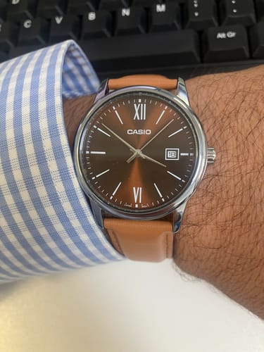 Primer plano del Reloj Casio Análogo en la muñeca de un cliente, con correa de cuero clara y esfera marrón.