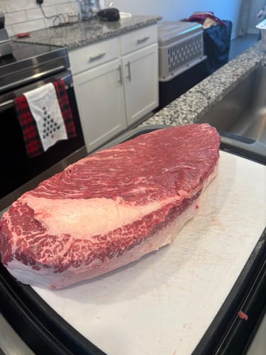 Customer's large, raw USDA Prime Brisket on a cutting board, showing excellent marbling.