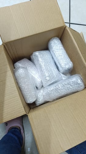Caja de envío de un cliente mostrando varios perfumes M068 envueltos en plástico de burbujas.