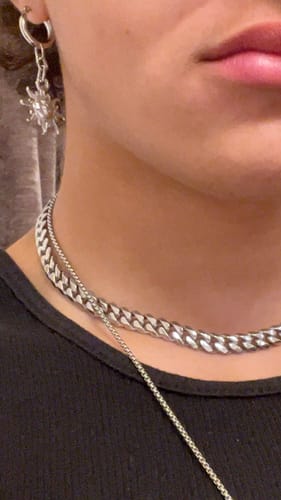 Close-up of a reviewer wearing the silver Sunny Dangle Earring in their ear, paired with other silver jewelry.