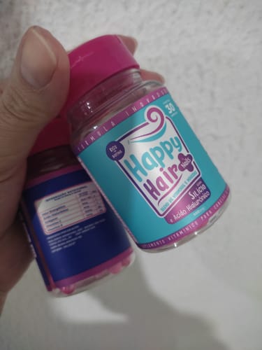 Cliente segurando dois potes do suplemento Happy Hair, mostrando o rótulo azul e a parte de trás.