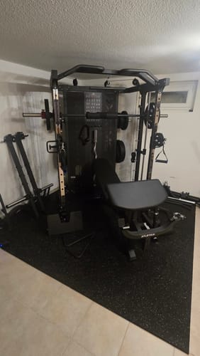 Rezensentenfoto der schwarzen SWAT Multipresse, die in einem Raum mit niedriger Decke und einer Hantelbank davor aufgebaut ist.