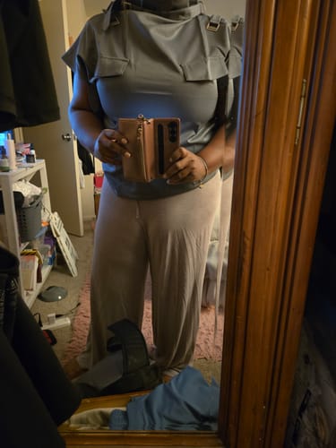 Reviewer taking a mirror selfie while wearing the deep gray sleeveless buckle top, showing the fit.