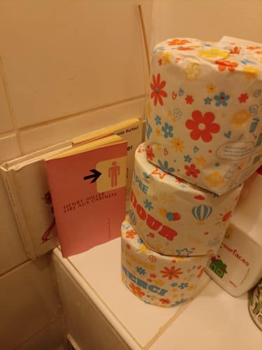 Photo d'un client montrant trois rouleaux de papier toilette Beau et Doux colorés et empilés dans une salle de bain.