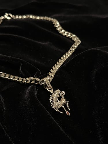 Customer's 8MM MINI CUBAN CHAIN with a detailed pendant laid on a plush black fabric.