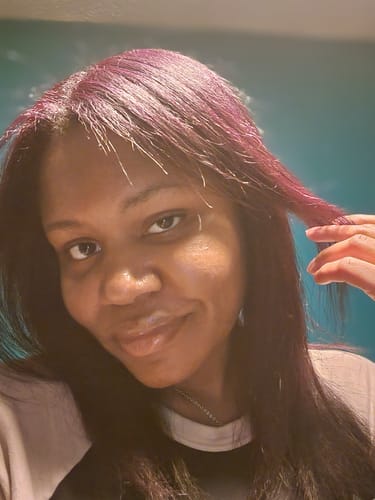 Reviewer holding a strand of hair to show the subtle purple color from the Instant Dye Shampoo.