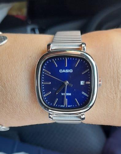 Una clienta luciendo su reloj Casio Análogo con esfera azul y correa de acero en la muñeca.