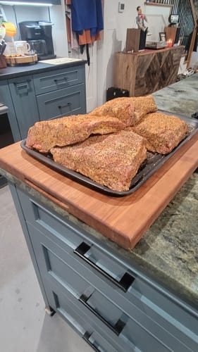 Customer's four raw USDA Choice Bone-In Short Ribs, seasoned and placed on a baking sheet in a kitchen.