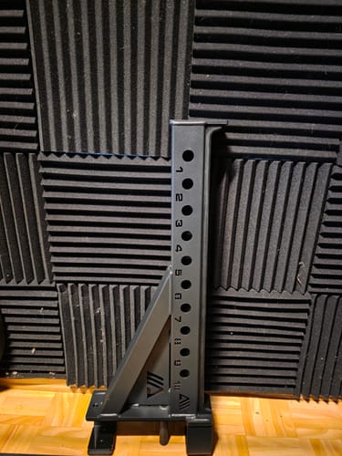 Rezensent zeigt einen einzelnen, schwarzen R7 Spotter Arm, der auf einem Holzboden steht.