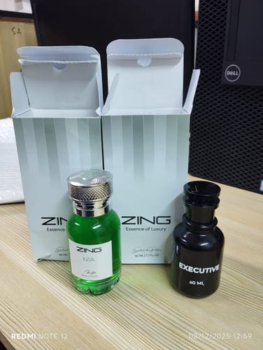 Customer's NIA perfume bottle with green liquid sitting on a desk next to another perfume and their boxes.