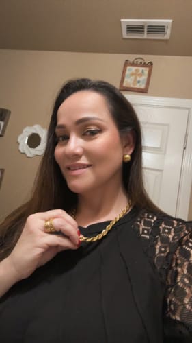Customer smiling while wearing the round, gold Bahama Bold Earrings with a black lace top.