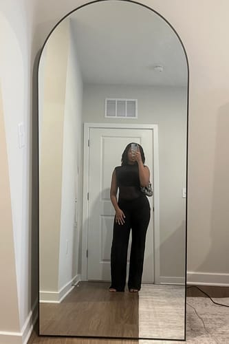 Reviewer in a full-length mirror photo wearing the black Hourglass Mesh Wide Leg Jumpsuit.