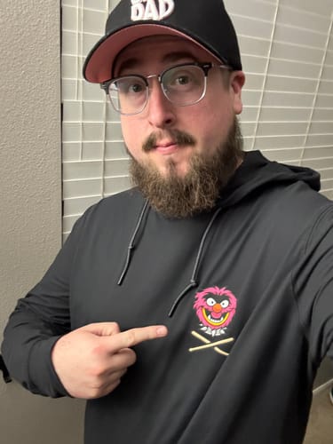 Reviewer pointing to the Animal graphic on the chest of their black 'DRUMMER!!!' performance hoodie.