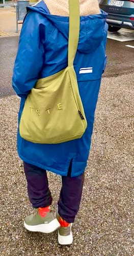 Customer from behind wearing the ALTA Khaki Green bag over their shoulder, styled with a blue coat.