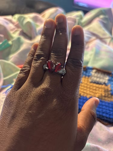 Customer's hand wearing the PROMISE RING, which has two red, coffin-shaped stones that form a heart.