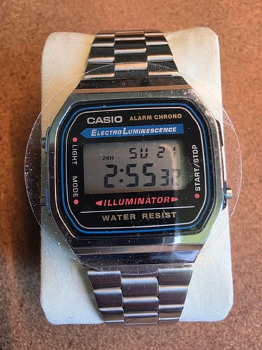 Primer plano del reloj Casio Vintage A168WA plateado de un cliente, mostrando la pantalla digital sobre un soporte.