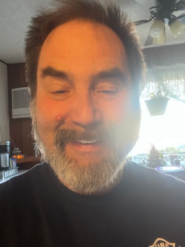 A customer with a beard smiling happily while wearing his Spare Veneers in a brightly lit room.