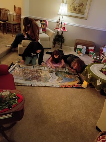Customer's family playing with the World's Greatest Search & Discover poster on a living room floor.