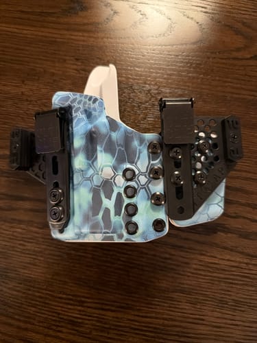 Customer's APX holster with a blue and black patterned design, shown on a dark wood surface.