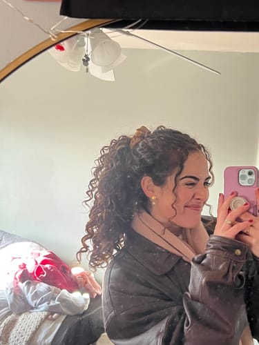 Reviewer smiling in a mirror selfie while wearing a small gold earring from the Advent Calendar.