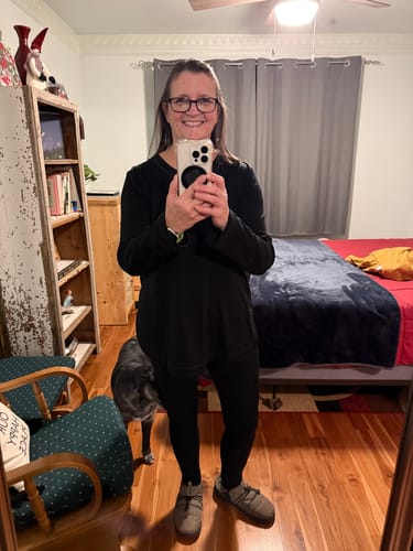 Customer takes a mirror selfie wearing the black Hazel Tunic, showing its loose fit and long length over leggings.