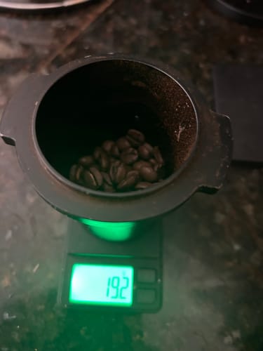 Customer weighing whole Gusto coffee beans on a digital scale before grinding.