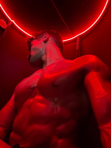 Close-up of a customer sweating inside their Sauna Pod 2.0, illuminated by the red light.