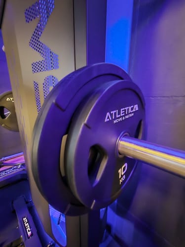 Ein Rezensent zeigt die schwarze, gummierte 10 kg 2H Gripper Plate auf einer Langhantel.