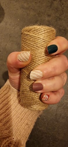 Hand einer Kundin mit aufgetragenen 'Blush Wonderland' UV-Gelnägeln, die ein elegantes Streifen- und Schneeflockenmuster zeigen.