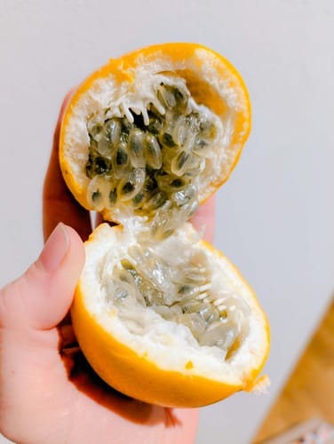 Rezensent hält eine aufgeschnittene gelbe Maracuja aus der Obstbox in der Hand.