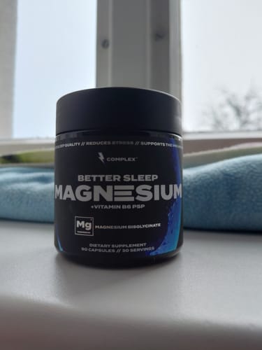 Reviewer's black tub of Complex Better Sleep Magnesium supplement resting on a windowsill in front of a blue towel.