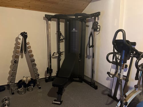 Das schwarze Compact Set eines Kunden, mit Kabelzugstation und Hantelbank, aufgestellt in einem Heim-Fitnessstudio.