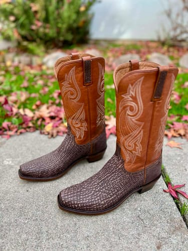 Customer's pair of Mingus Western Boots on a stone patio, highlighting the textured shark leather and stitched shafts.